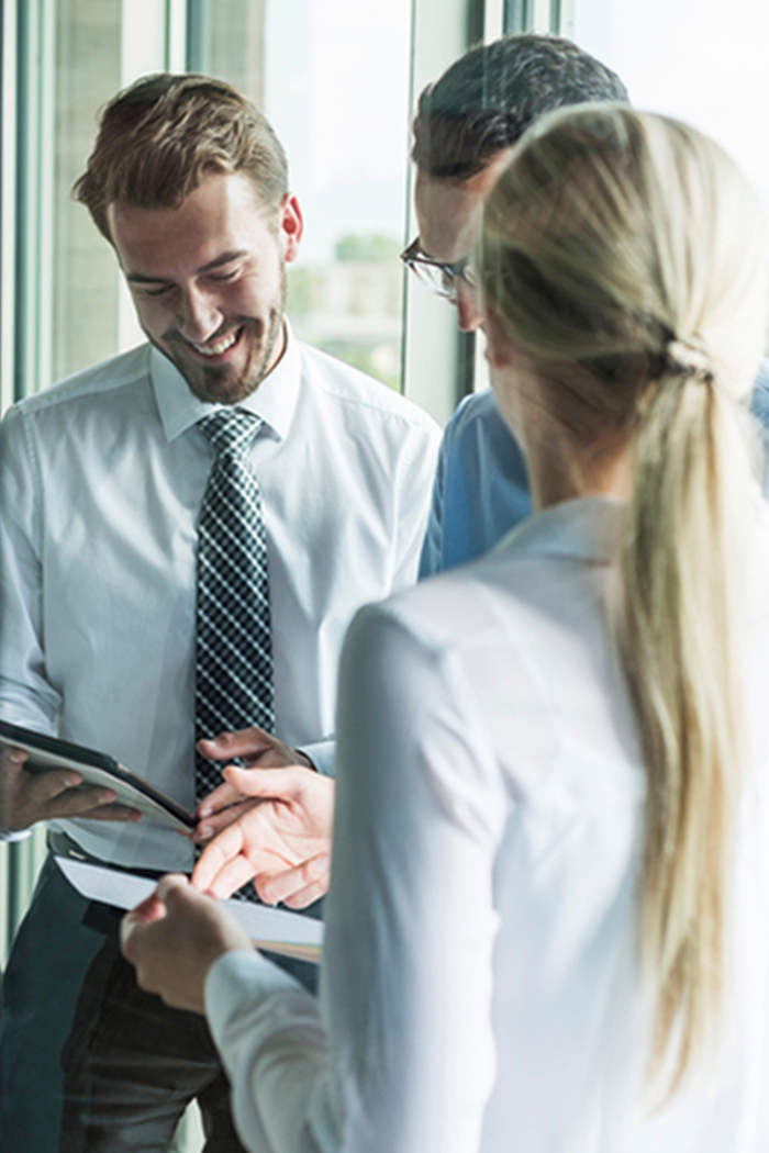 Three young businesspeople looking at documents and digital tablet